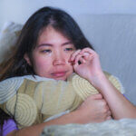 young sad and depressed Asian Korean woman at home sofa couch crying ...