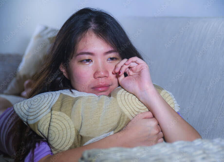 young sad and depressed Asian Korean woman at home sofa couch crying ...